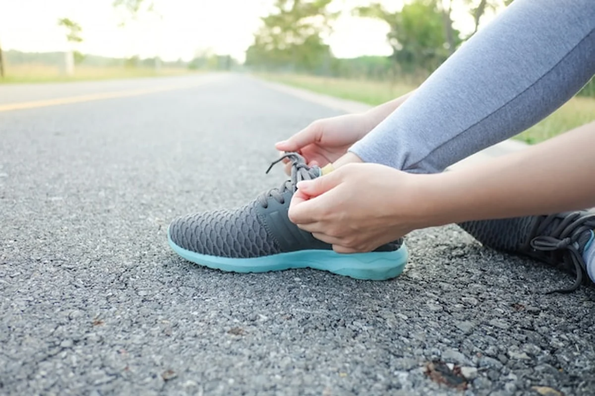Sportowa kobieta wiążąca sznurowadło na butach do biegania przed treningiem