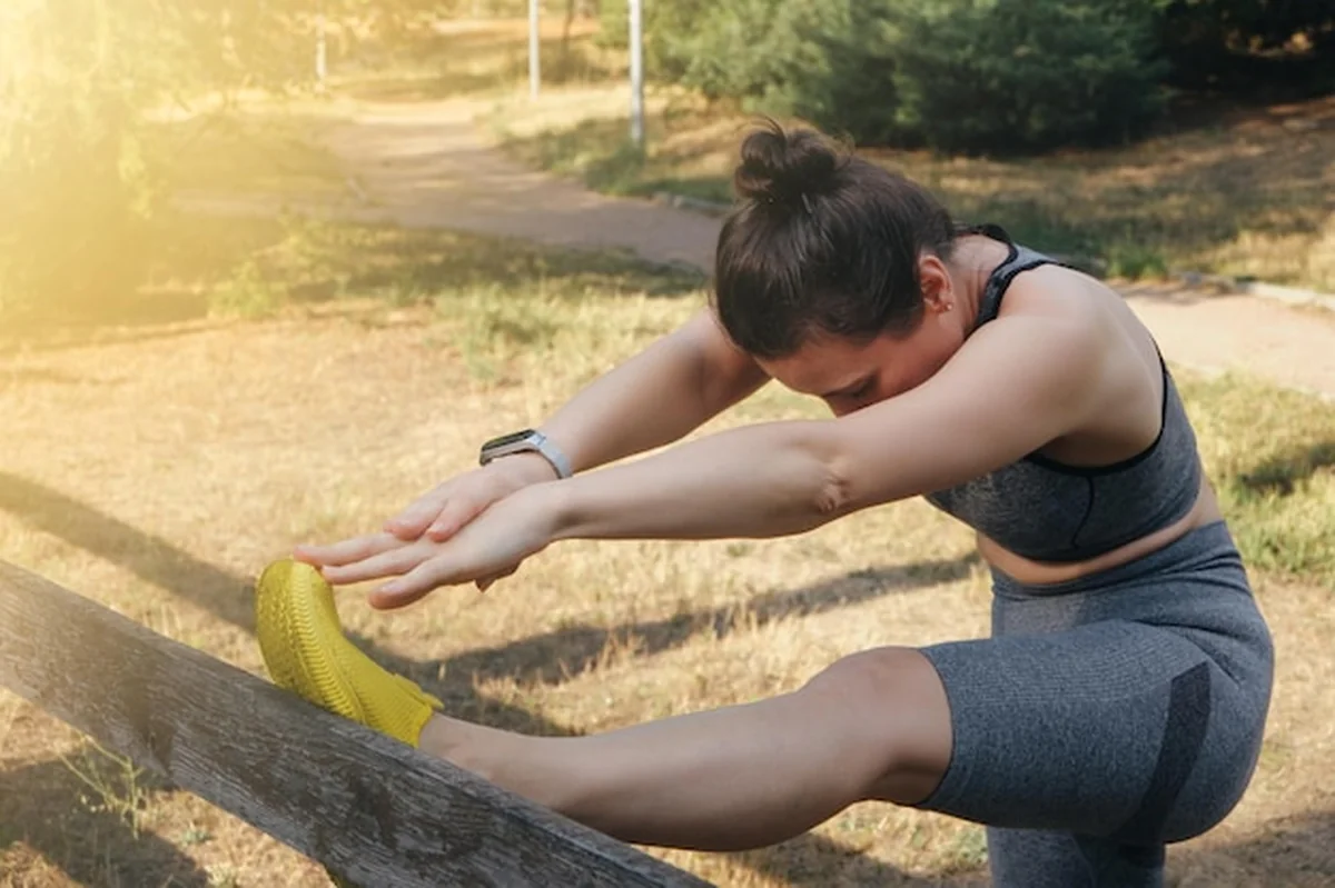 Młoda kobieta robi ćwiczenia w parku w słoneczny letni dzień