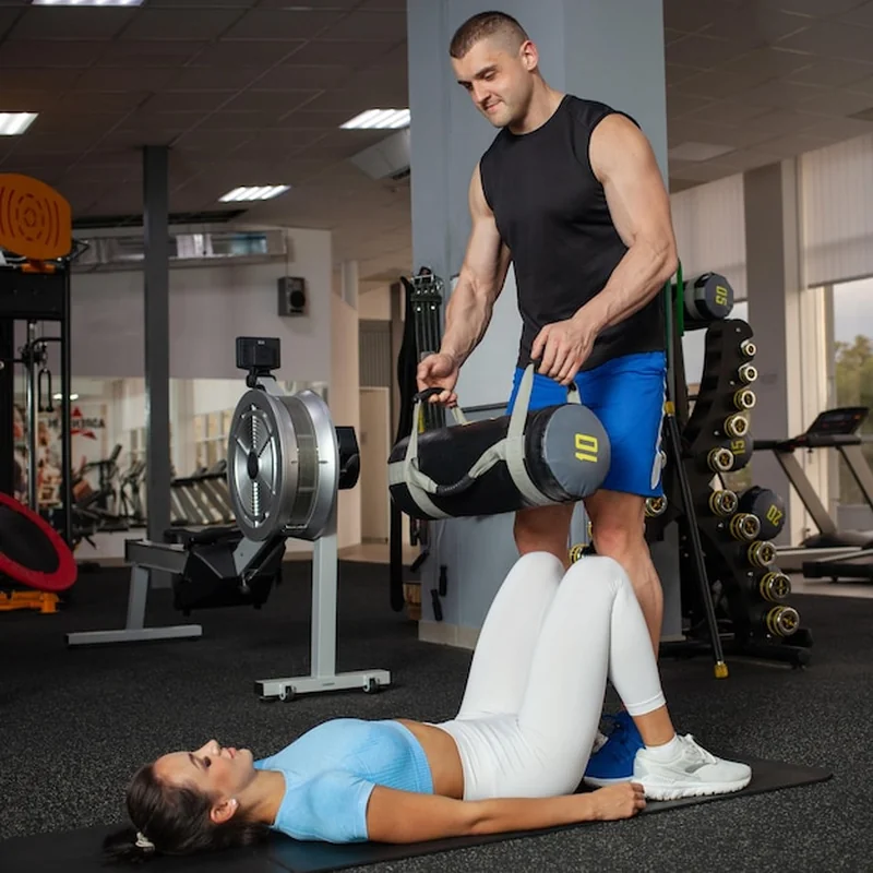 Trener pomaga kobiecie w ćwiczeniu z obciążeniem