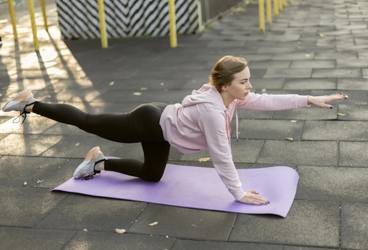 Kobieta ćwiczy równowagę na macie do jogi na boisku sportowym