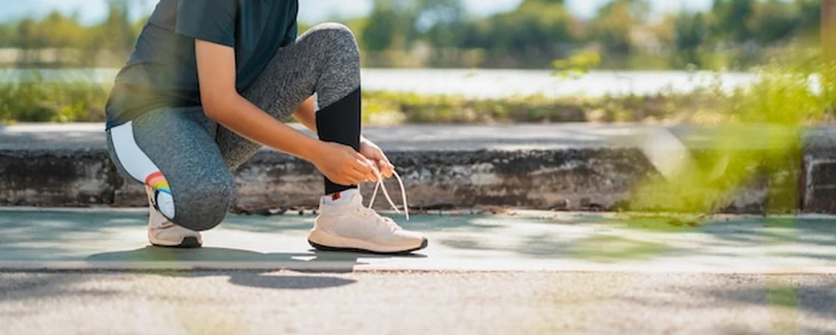 Kobieta wiążąca sznurowadła do biegania w parku