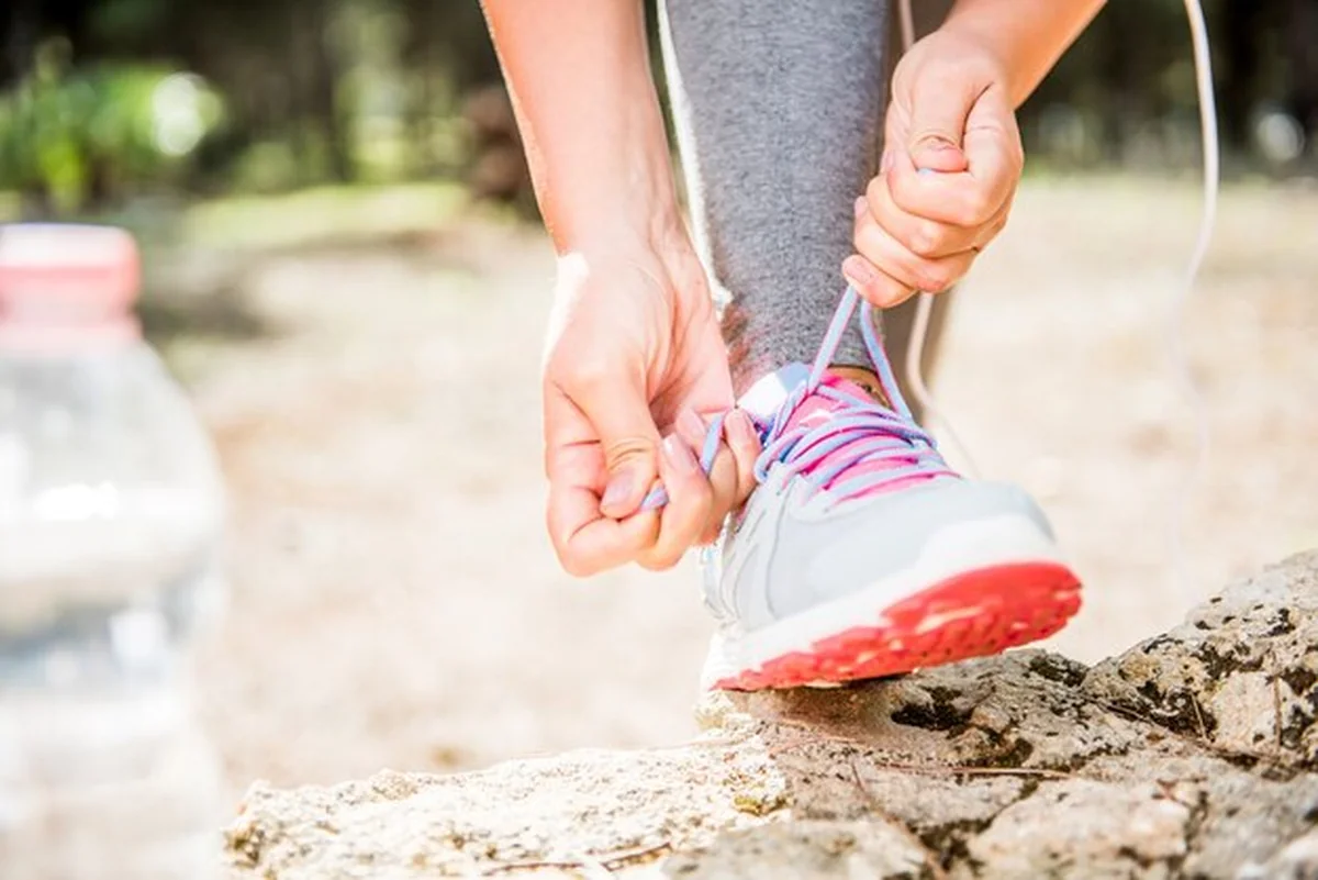 Kobieta wiąże sznurowadła do butów przed biegiem na świeżym powietrzu