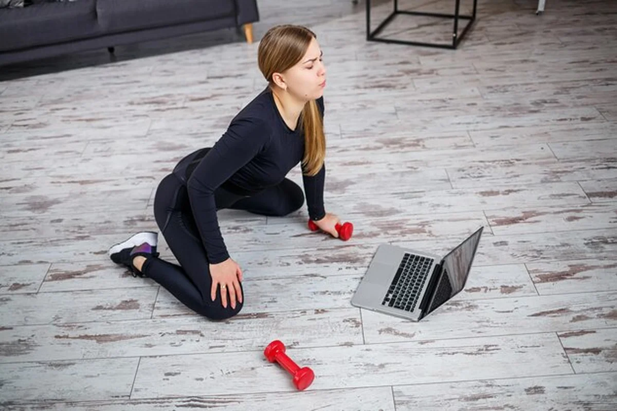 Młoda sportowa kobieta ćwiczy w domu z laptopem