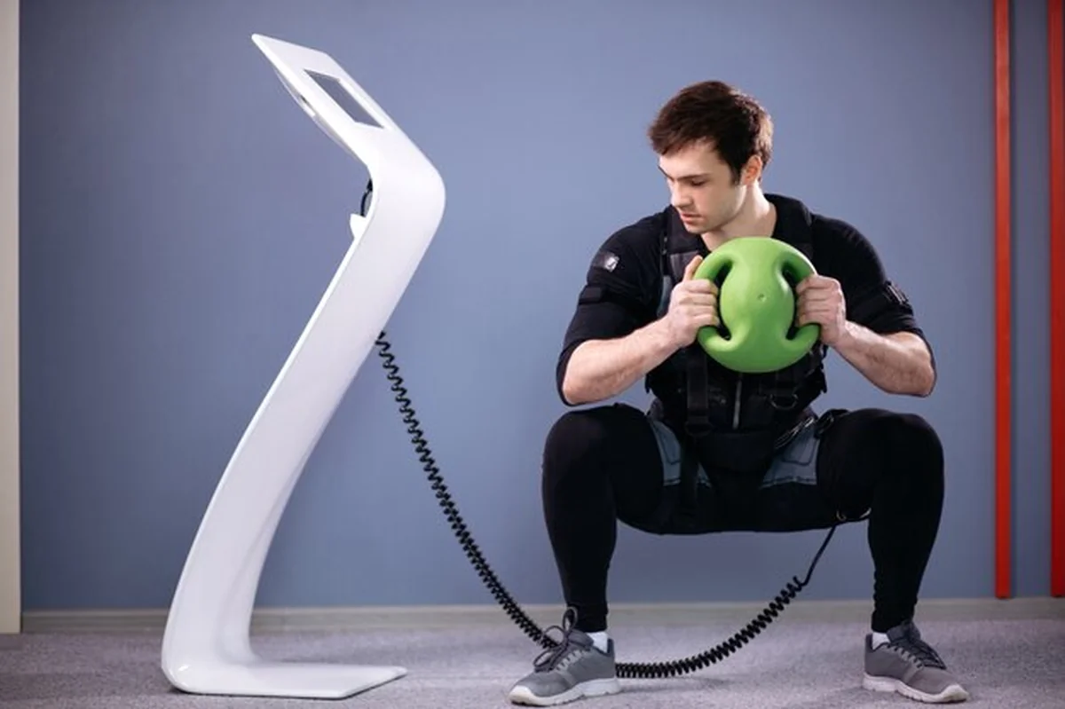 Mężczyzna wykonujący trening EMS z piłką medyczną