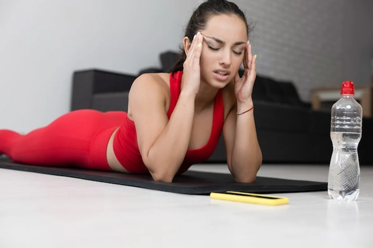 Młoda kobieta w czerwonym dresie wykonuje ćwiczenia jogi w domu