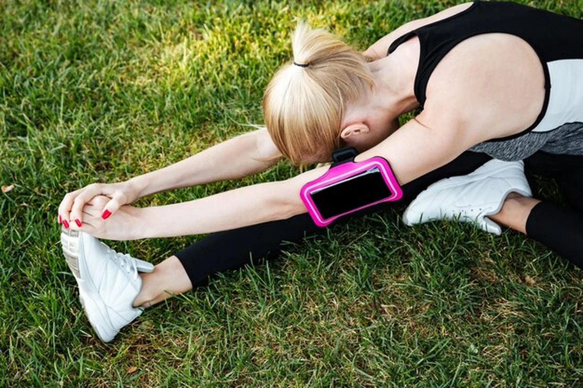 Młoda kobieta biegaczka rozciągająca nogi w parku