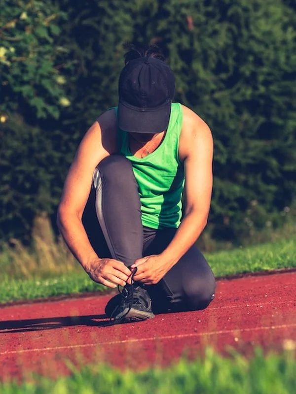 Kobieta biegaczka wiążąca sznurowadła na torze stadionu