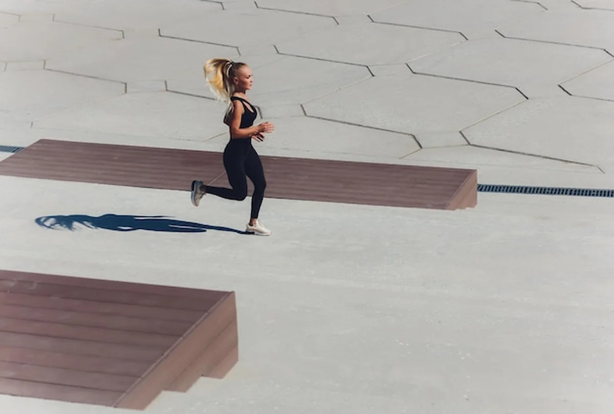 Biegaczka biegnie o wschodzie słońca na nabrzeżu w mieście