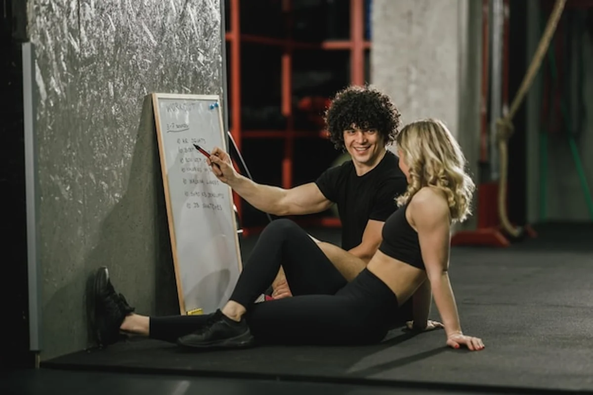 Atrakcyjna kobieta na siłowni z osobistym trenerem