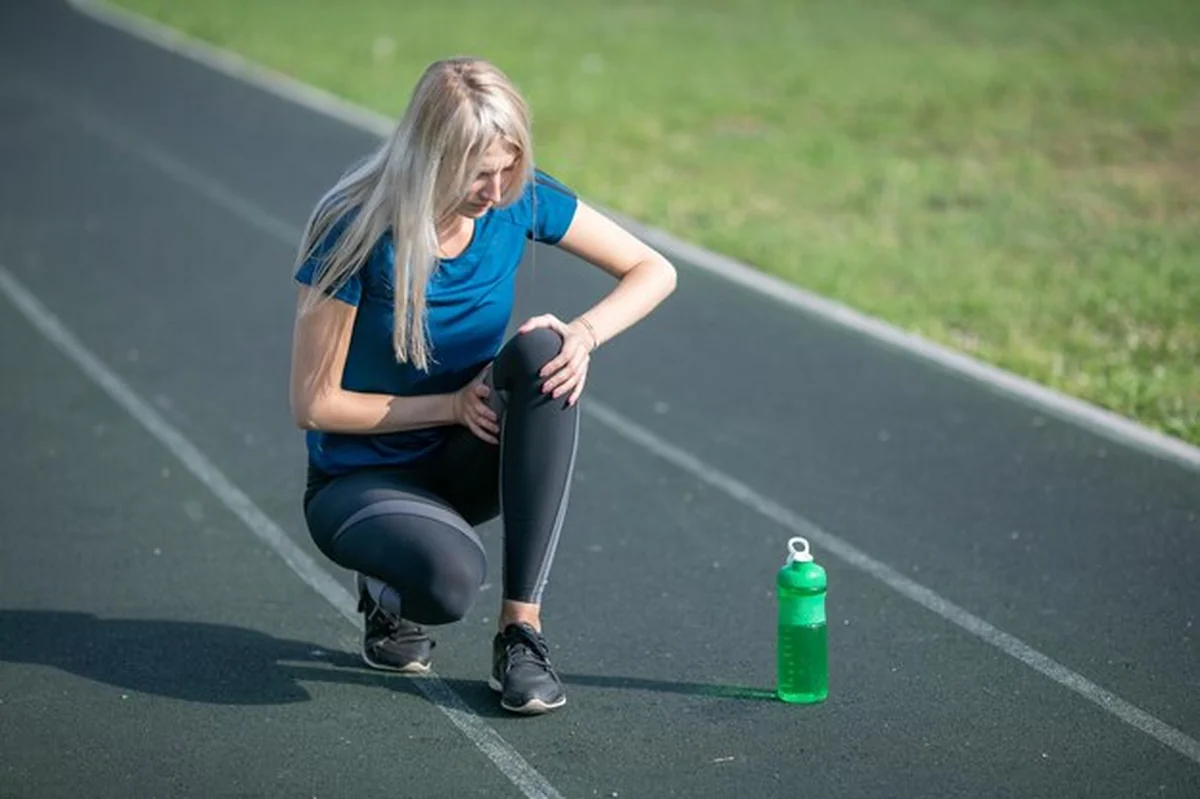 Kobieta po kontuzji kolana na bieżni z butelką sportową